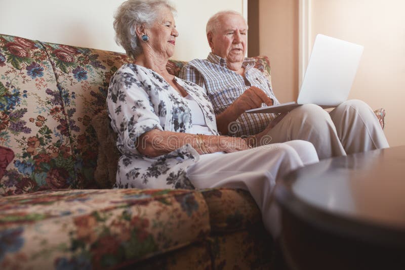 Ältere Paare, die auf Sofa sich entspannen und Laptop verwenden stockfotos Ältere Paare, die auf Sofa sich entspannen und Laptop verwenden stockfotos