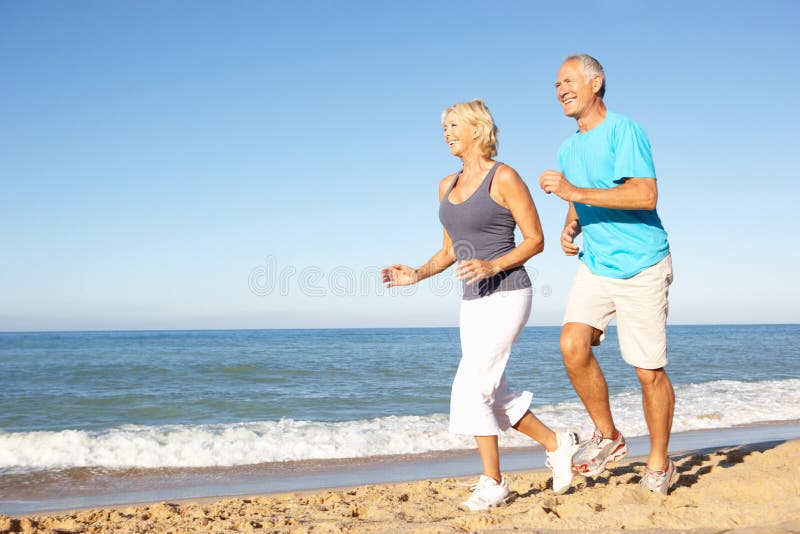 Ältere Paare, die entlang Strand laufen stockbild Ältere Paare, die entlang Strand laufen stockbild