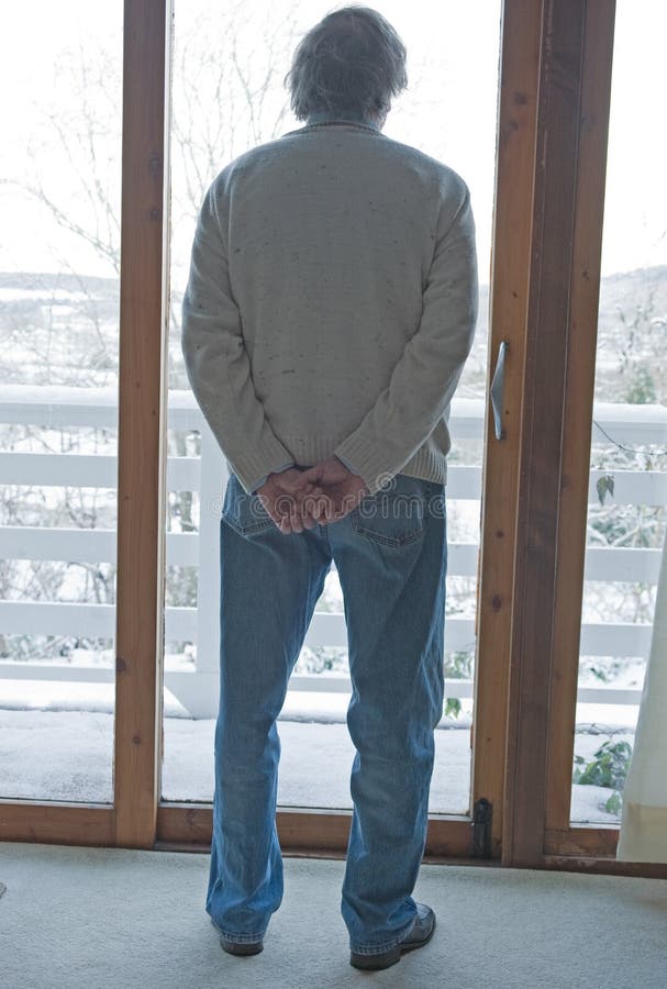 An image of a Senior looking out of a window over a balcony at a landscape of deep snow. An image of a Senior looking out of a window over a balcony at a landscape of deep snow.