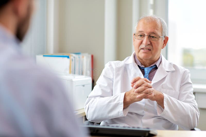 Älterer Doktor, der mit männlichem Patienten am Krankenhaus spricht lizenzfreies stockfoto Älterer Doktor, der mit männlichem Patienten am Krankenhaus spricht lizenzfreies stockfoto