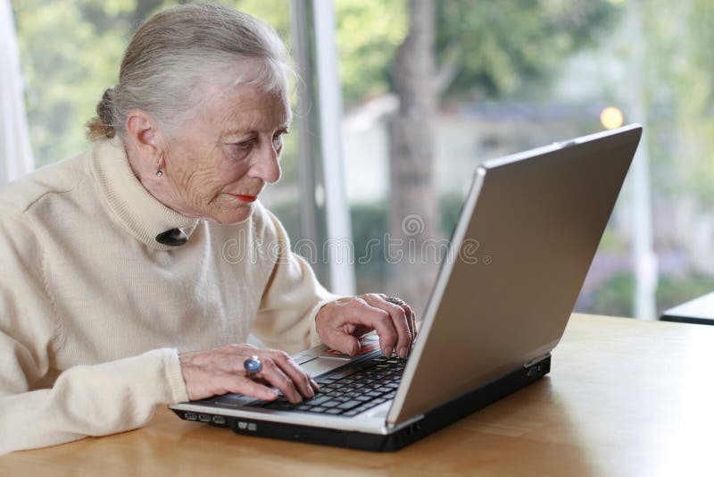 Elderly lady typing on laptop. Shallow DOF, focus on senior woman. Elderly lady typing on laptop. Shallow DOF, focus on senior woman.