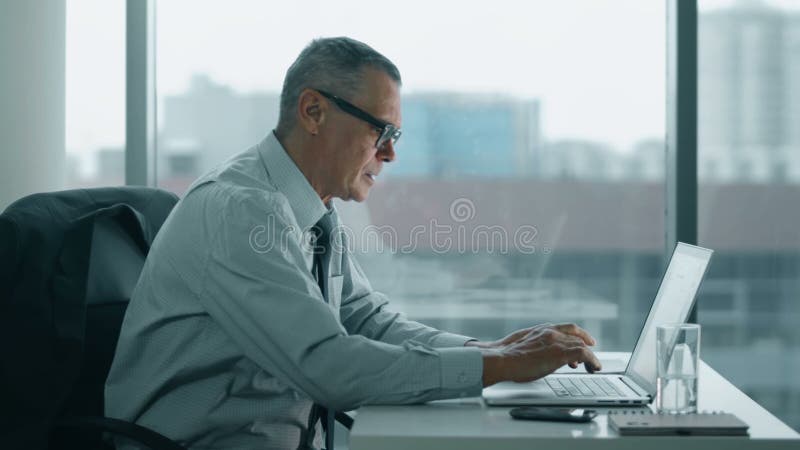 Älterer Geschäftsmann, der mit Computer im modernen Büro arbeitet seiner zurück ist Schmerzen