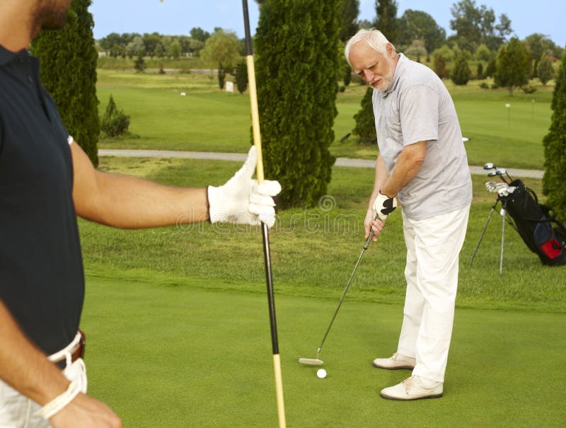 Älterer Golfspieler, der auf Ball sich konzentriert stockbild Älterer Golfspieler, der auf Ball sich konzentriert stockbild