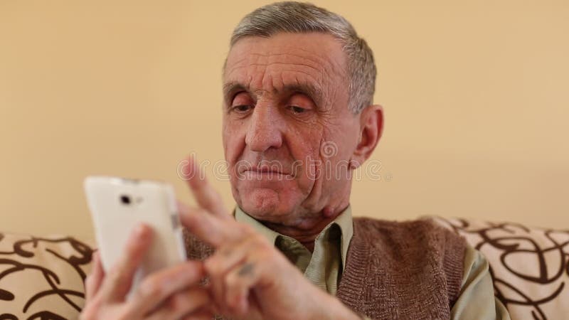 Älterer Mann, der durch die Fotos in ihrem Smartphone schaut und leicht schlägt stock video footage Älterer Mann, der durch die Fotos in ihrem Smartphone schaut und leicht schlägt stock video footage