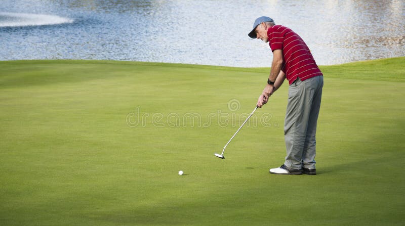 Älterer Mann, der Golf durch einen See spielt stockfoto Älterer Mann, der Golf durch einen See spielt stockfoto