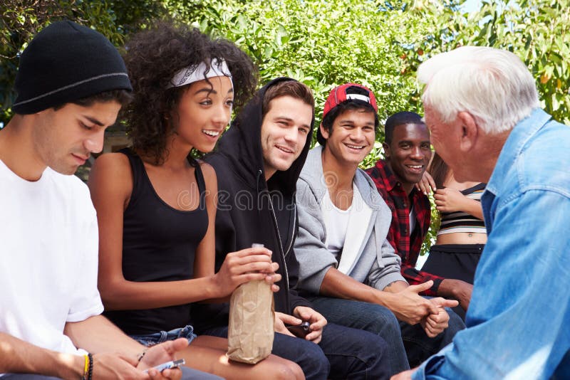 Älterer Mann, der mit Gruppe von jungen Leuten spricht stockfoto Älterer Mann, der mit Gruppe von jungen Leuten spricht stockfoto