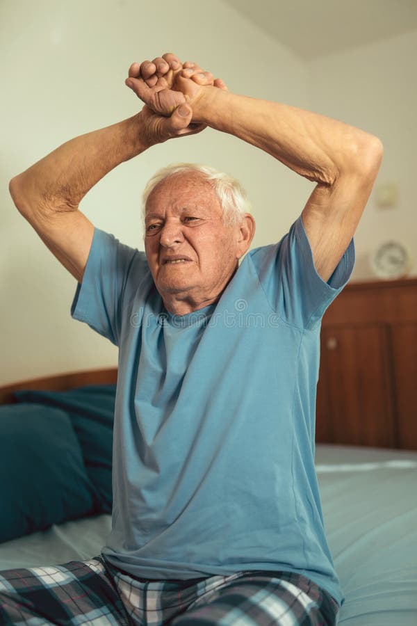Älterer Mann, der in Schlafzimmer ausdehnt stockbild Älterer Mann, der in Schlafzimmer ausdehnt stockbild