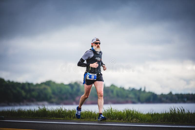 Älterer Marathoner allein auf der Seite der Straße und des Ozeans lizenzfreie stockfotografie Älterer Marathoner allein auf der Seite der Straße und des Ozeans lizenzfreie stockfotografie
