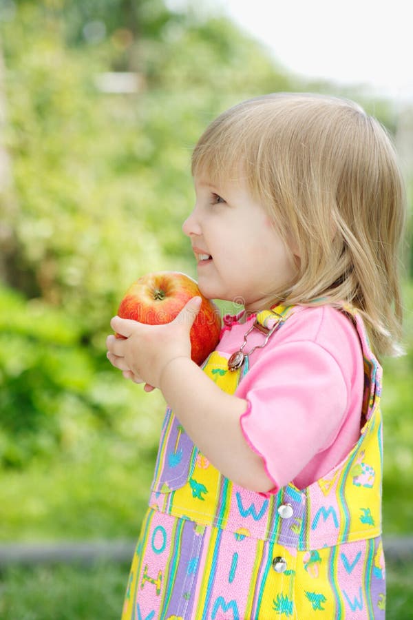 The little girl holds an apple in hands. The little girl holds an apple in hands