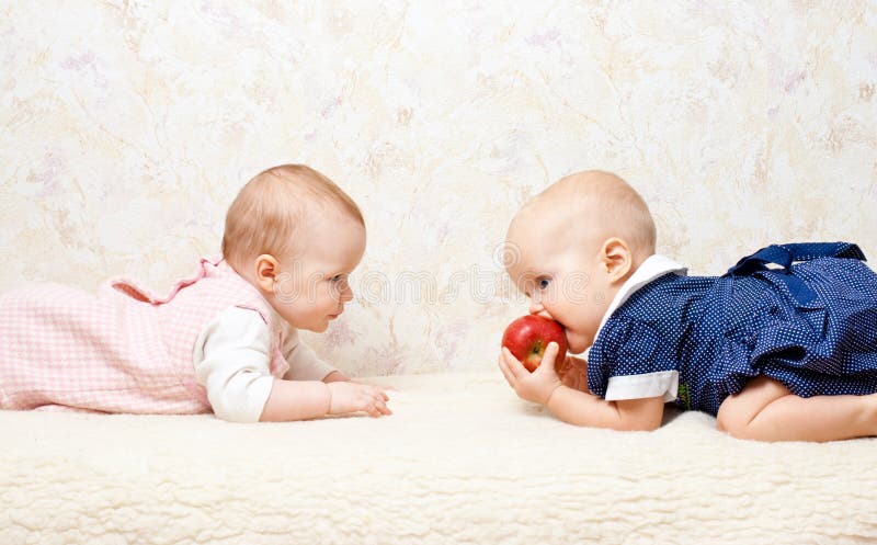 Two little baby girls playing with apple. Two little baby girls playing with apple