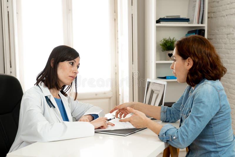 Ärztin, die auf den Frauenpatienten erklärt ihre Symptome und Gesundheitsprobleme hört lizenzfreies stockfoto Ärztin, die auf den Frauenpatienten erklärt ihre Symptome und Gesundheitsprobleme hört lizenzfreies stockfoto