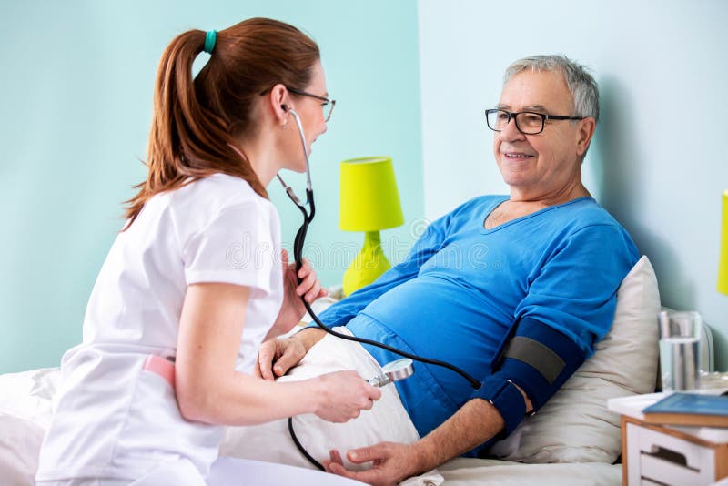 Ärztin, die Betreuung in der Pflegeeinrichtung zu einem älteren Mann vorsieht lizenzfreie stockfotografie