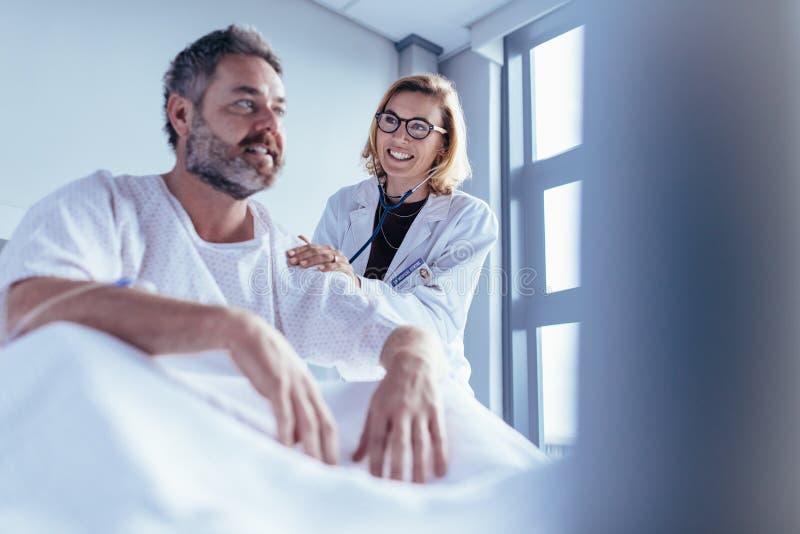 Ärztin, die männlichen Patienten im Krankenhauszimmer überprüft lizenzfreies stockbild Ärztin, die männlichen Patienten im Krankenhauszimmer überprüft lizenzfreies stockbild