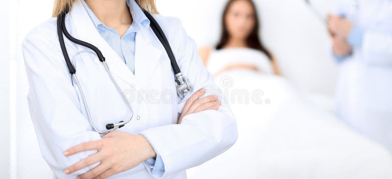 Ärztin mit dem Stethoskop, das mit den gekreuzten Armen, unbekannter Arzt bei der Arbeit aufrecht steht Stethoskop liegt auf Set lizenzfreies stockbild Ärztin mit dem Stethoskop, das mit den gekreuzten Armen, unbekannter Arzt bei der Arbeit aufrecht steht Stethoskop liegt auf Set lizenzfreies stockbild