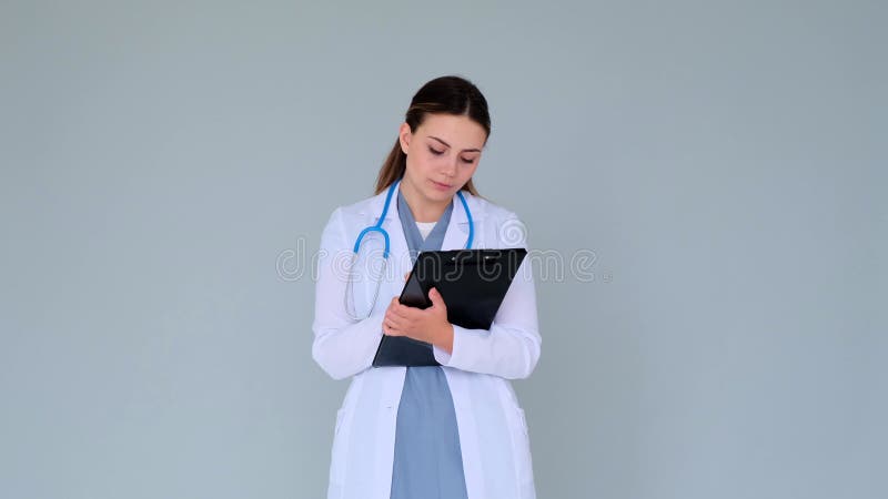 Ärztin oder Krankenschwester, die eine ärztliche Verschreibung auf Tablette mit grauem Hintergrund schreibt stock footage