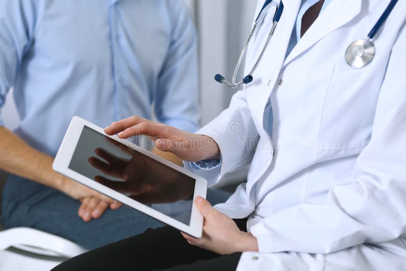 Ärztin unter Verwendung der Berührungsfläche oder des Tablet-Computers bei der Konsultierung des Mannpatienten im Krankenhaus Med stockbilder