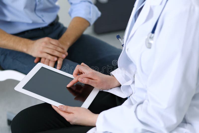 Ärztin unter Verwendung der Berührungsfläche oder des Tablet-Computers bei der Konsultierung des Mannpatienten im Krankenhaus Med lizenzfreie stockfotos