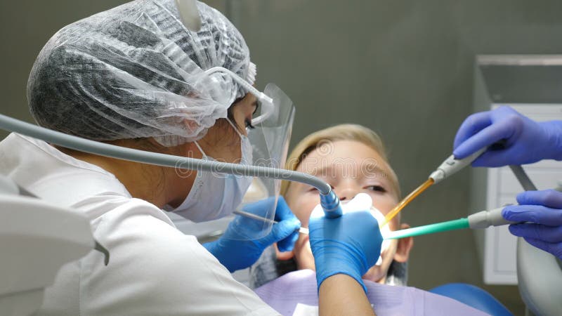 Ärztin, während einer Zahnbehandlung Behandlung Plastikschutzschild, Arzt im Gesichtsschutz trägt: Maske und Bildschirm