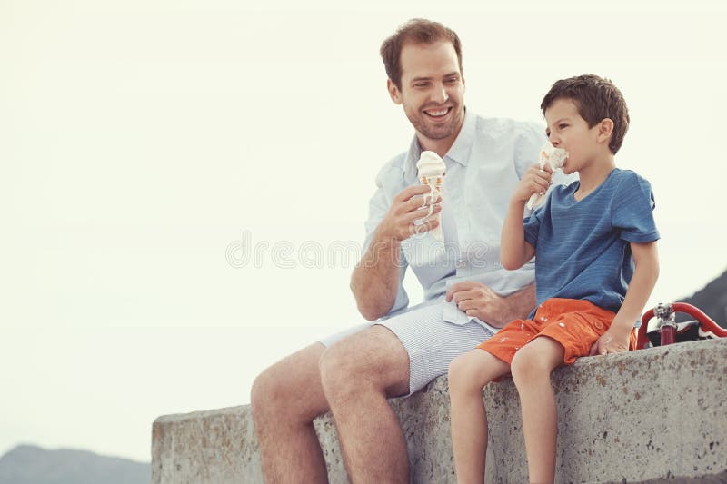 Father and son eating icecream together at the beach on vacation having fun with melting mess. Father and son eating icecream together at the beach on vacation having fun with melting mess