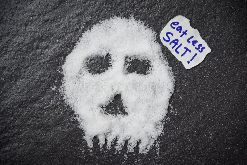 Äta mindre saltar för vård- begrepp/hög av vit saltar skalleform på mörk bakgrund arkivbild Äta mindre saltar för vård- begrepp/hög av vit saltar skalleform på mörk bakgrund arkivbild