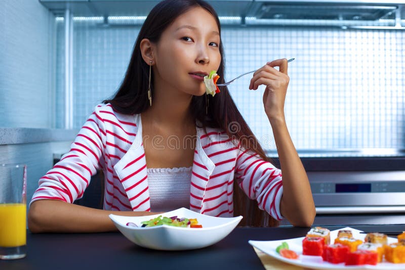 Young asian woman eating salad. Young asian woman eating salad.