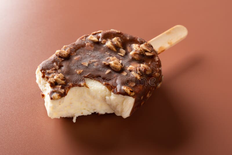 Äußere Eiscreme der Seitenansichtschokolade mit Erdnüssen auf einem braunen Hintergrund mit irgendeinem Biss stockbild Äußere Eiscreme der Seitenansichtschokolade mit Erdnüssen auf einem braunen Hintergrund mit irgendeinem Biss stockbild