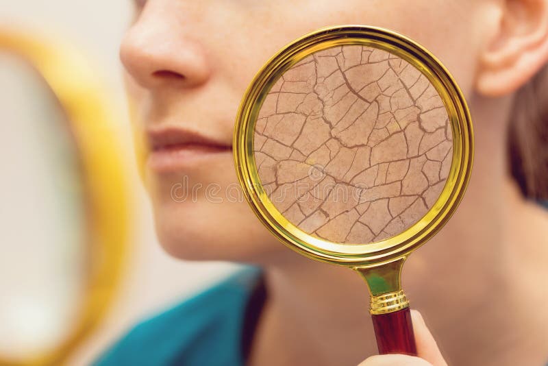 Aging and dry face skin concept - woman with magnifying glass checking cheek. Aging and dry face skin concept - woman with magnifying glass checking cheek