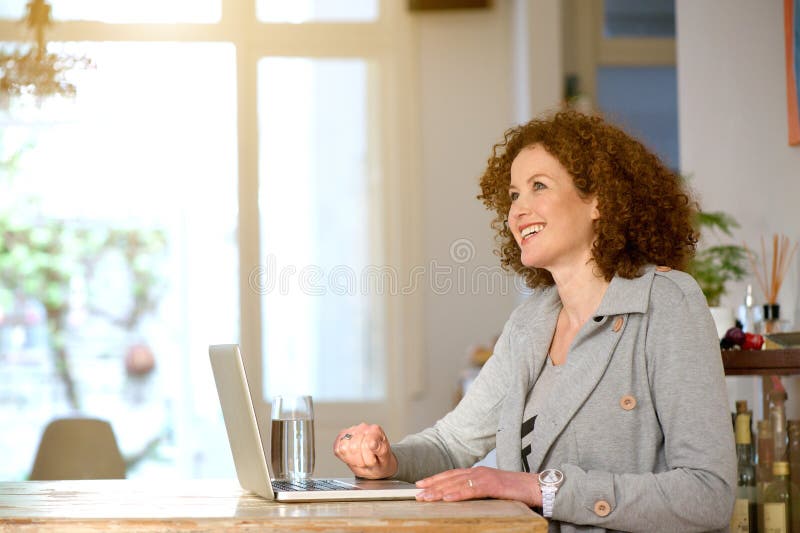 Åldrig kvinna för lycklig mitt som hemma använder bärbara datorn