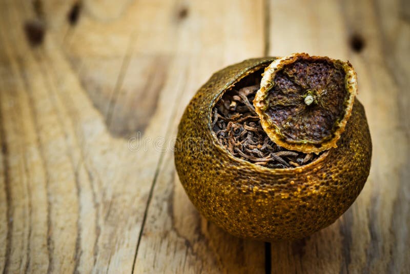 Åldrigt jäst svart kinesiskt puerte i en tangerinpeel med locket, riden ut wood bakgrund, slut upp arkivbild Åldrigt jäst svart kinesiskt puerte i en tangerinpeel med locket, riden ut wood bakgrund, slut upp arkivbild