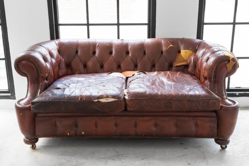 årgångsformat. defekt gammal lädersofa på vitt rum arkivbilder