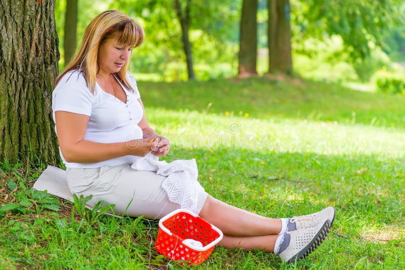 50-year-old woman knitting in the summer park. 50-year-old woman knitting in the summer park