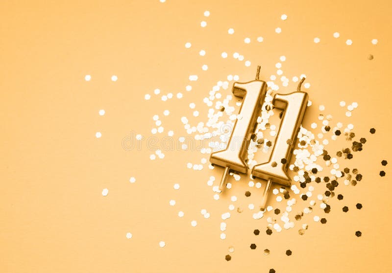 11 years birthday celebration festive background made with golden candle in the form of number Eleven lying on sparkles. Universal holiday banner with copy space. 11 years birthday celebration festive background made with golden candle in the form of number Eleven lying on sparkles. Universal holiday banner with copy space