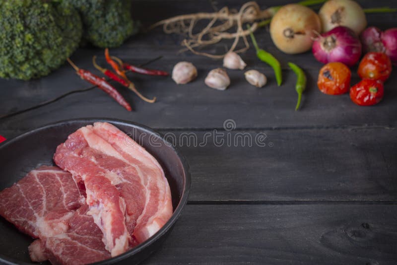 Świeża wieprzowina w czarnej niecce, umieszczającej na drewnianym stole z pikantność umieszczać wokoło zdjęcie stock