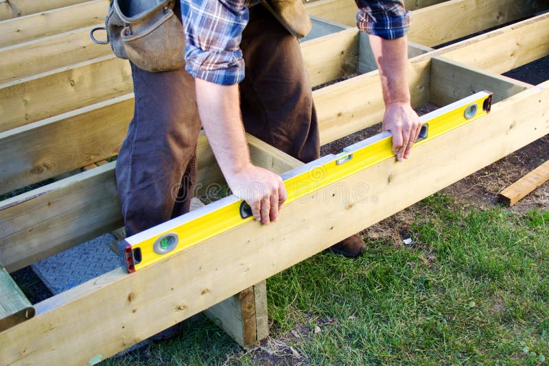 Carpenter checking level of deck boards. Carpenter checking level of deck boards