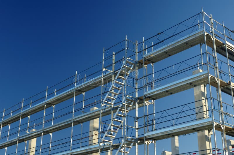 Scaffolding on a construction site, against a clear blue sky. Scaffolding on a construction site, against a clear blue sky.