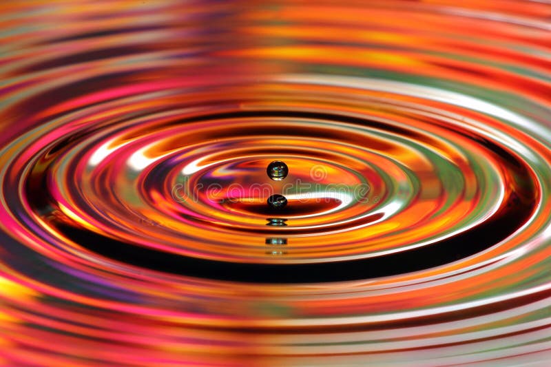 Water drops splash. Red and yellow colored ripples, reflections on water surface. Water drops splash. Red and yellow colored ripples, reflections on water surface.