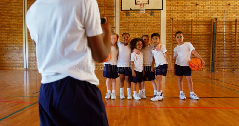 Écolier cliquant sur la photo avec le téléphone portable de ses amis au terrain de basket à l'école 4k clips vidéos