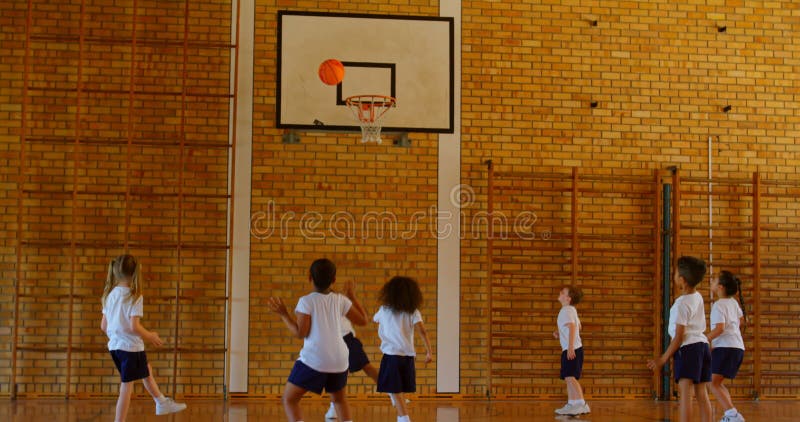 Écoliers pratiquant le basket-ball au terrain de basket à l'école 4k banque de vidéos