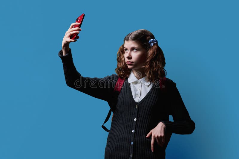 écolière préadolescente avec sac à dos prenant selfie photo par smartphone sur fond bleu photos libres de droits