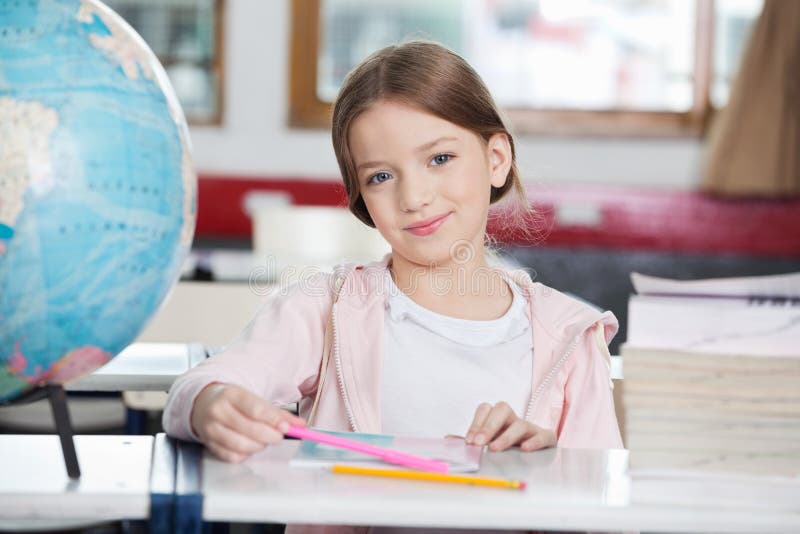 Écolière souriant avec les livres et le globe au bureau images libres de droits Écolière souriant avec les livres et le globe au bureau images libres de droits