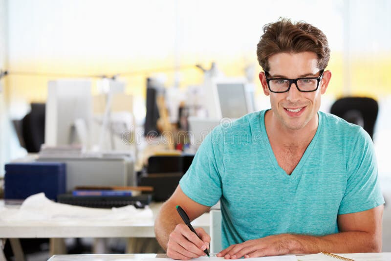 Écriture d'homme au bureau dans le bureau créatif occupé images stock Écriture d'homme au bureau dans le bureau créatif occupé images stock