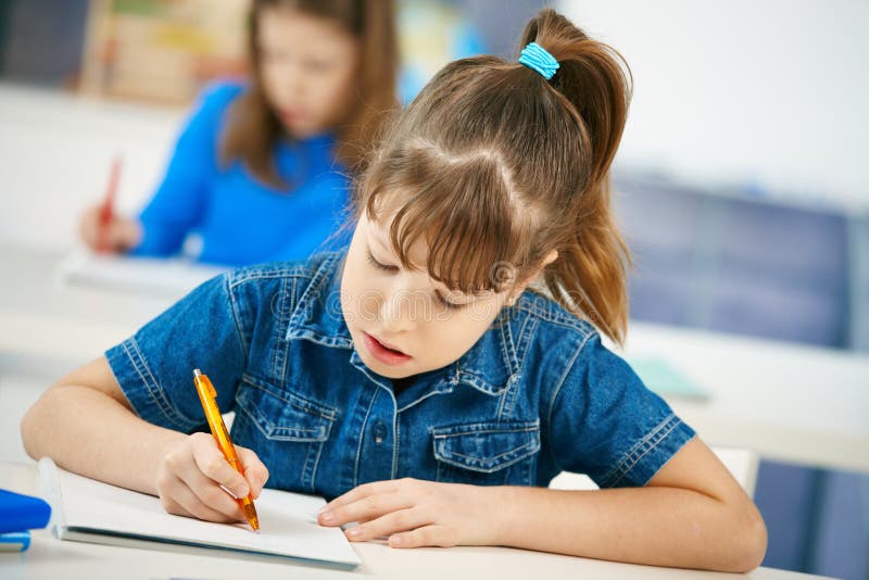 Écriture de jeune fille à l'école photos stock