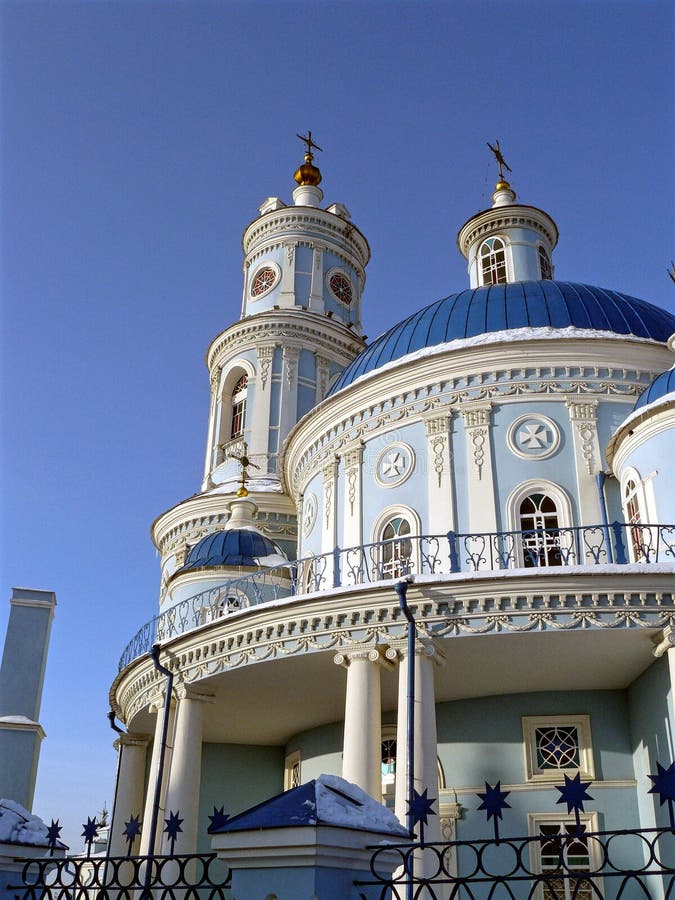 The Church of the rotunda, with round bell tower, Golden crosses and domes. Painted blue and white paint, blue sky. The Church of the rotunda, with round bell tower, Golden crosses and domes. Painted blue and white paint, blue sky.