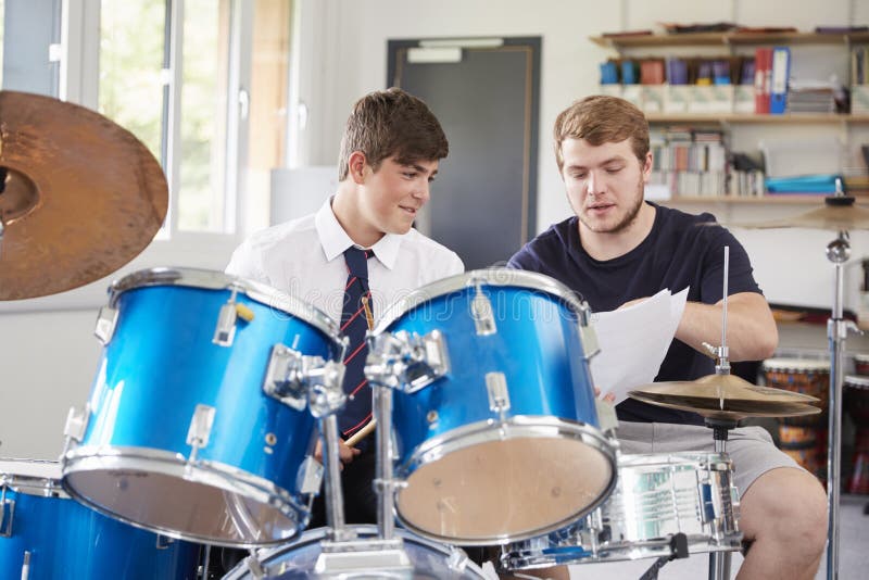 Élève masculin avec la leçon de musique de Playing Drums In de professeur photo libre de droits Élève masculin avec la leçon de musique de Playing Drums In de professeur photo libre de droits