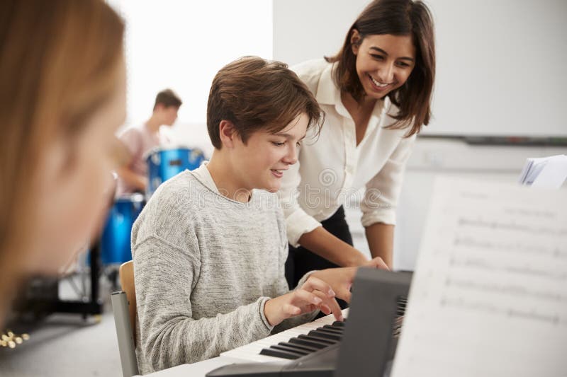 Élève masculin avec la leçon de musique de Playing Piano In de professeur image stock Élève masculin avec la leçon de musique de Playing Piano In de professeur image stock