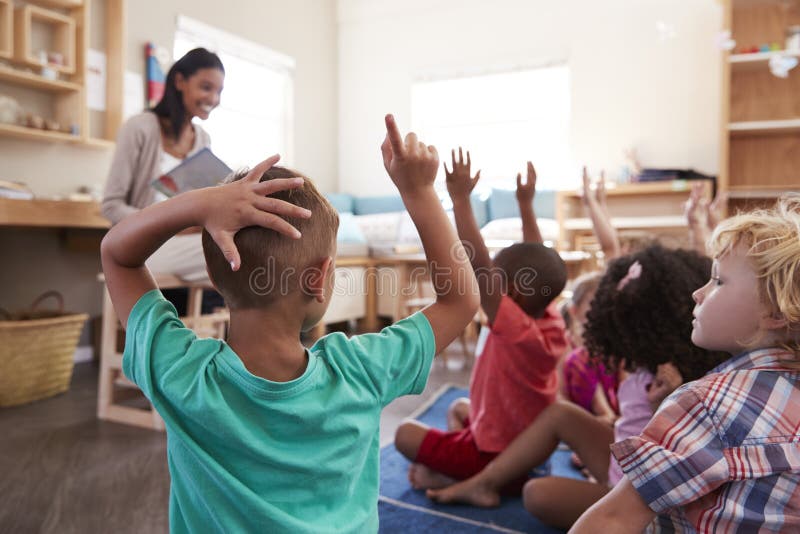Élèves à l'école de Montessori soulevant des mains pour répondre à la question photo libre de droits Élèves à l'école de Montessori soulevant des mains pour répondre à la question photo libre de droits