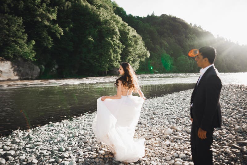élégant joli marié blonde et beau marié sur le fond d'une belle rivière dans les montagnes photo libre de droits