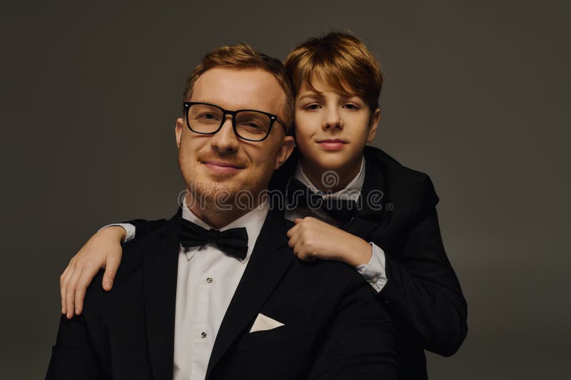 Élégant père et fils habillés en. Père et fils ont l'air pointu dans des tuxedos capturant un lien intemporel dans un studio élégant.