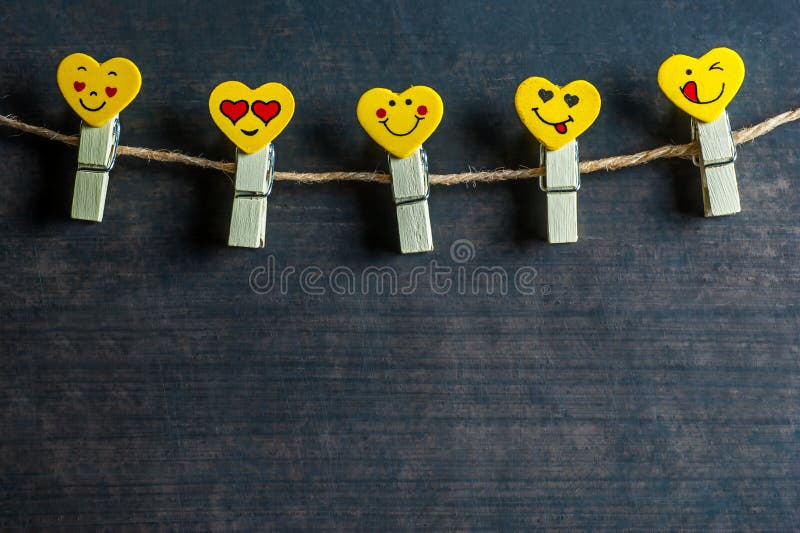 Émotions jaunes de coeurs d'amour ou pinces à linge ou chevilles d'émoticônes sur une corde sur le fond rustique en bois de cru