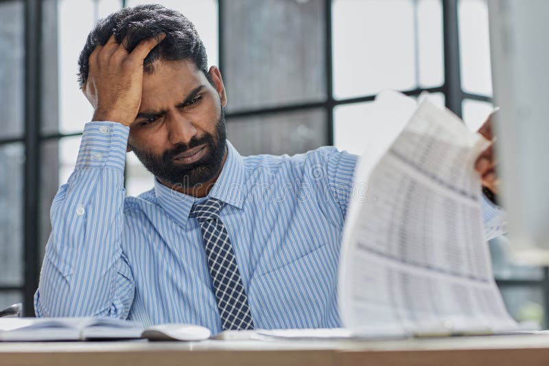 Frustrated overwhelmed executive working in the office and overloaded with paperwork, he is leaning on his arm and feeling depressed. Frustrated overwhelmed executive working in the office and overloaded with paperwork, he is leaning on his arm and feeling depressed